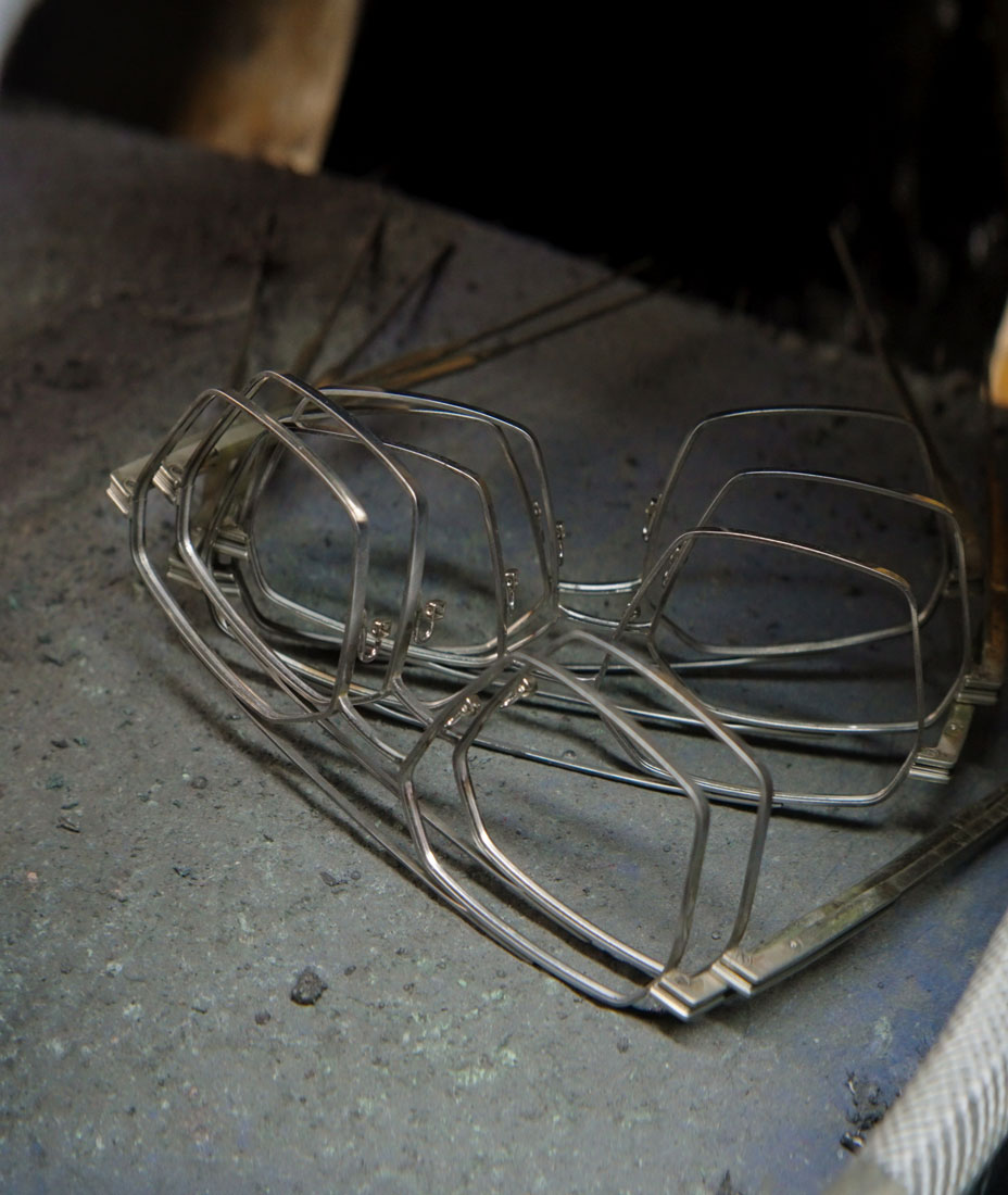 Cinematic vertical anamorphic shop of the titanium frame for James Oro glasses being polished in the factory floor.