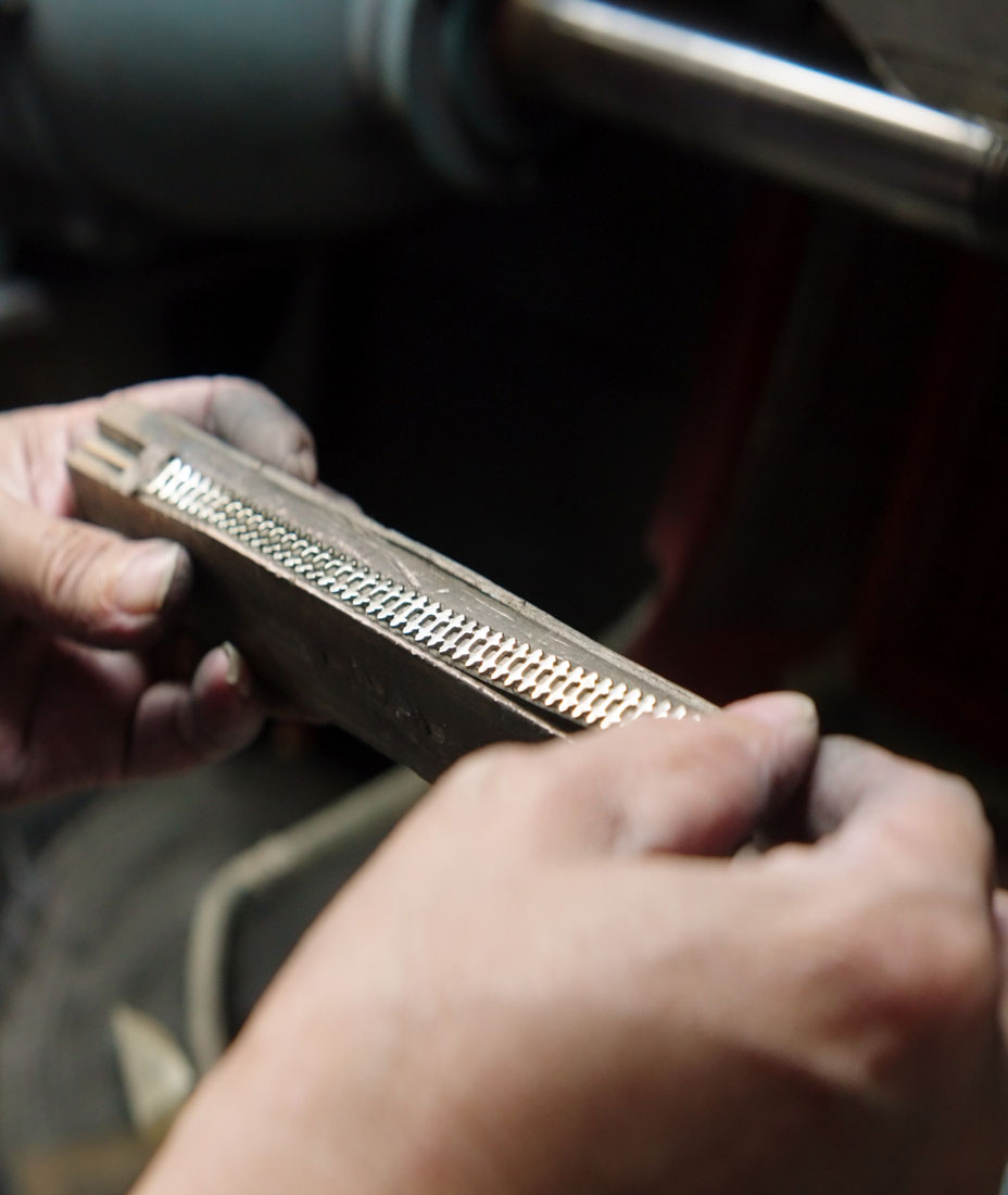 Cinematic vertical anamorphic shop of the titanium frame for James Oro glasses being polished in the factory floor.